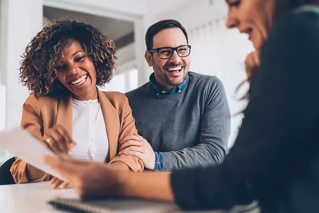 A couple reviewing insurance paperwork with their agent at a table.
