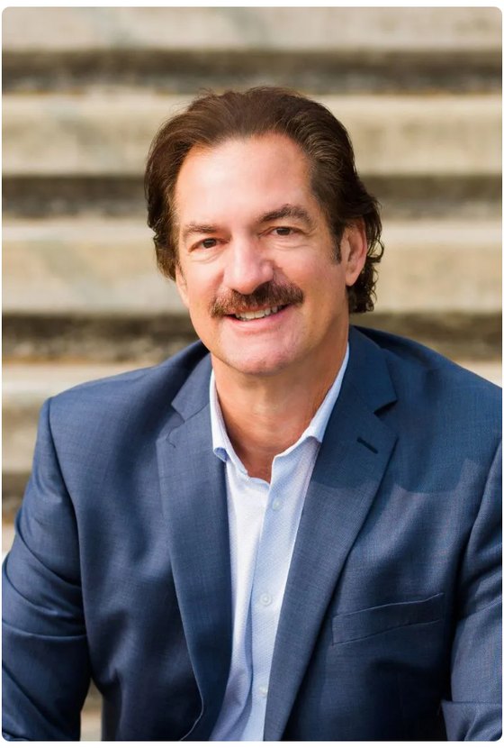 Frank Biaggi, founder of Biaggi Life, seated outdoors in a navy suit.