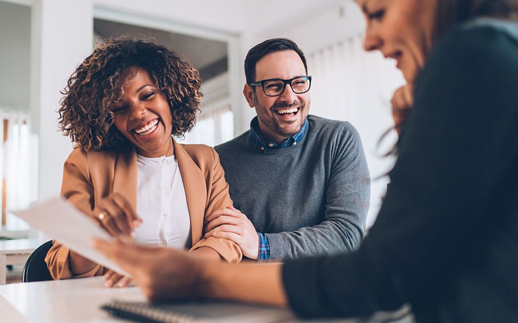A couple smiling during a meeting with their agent.