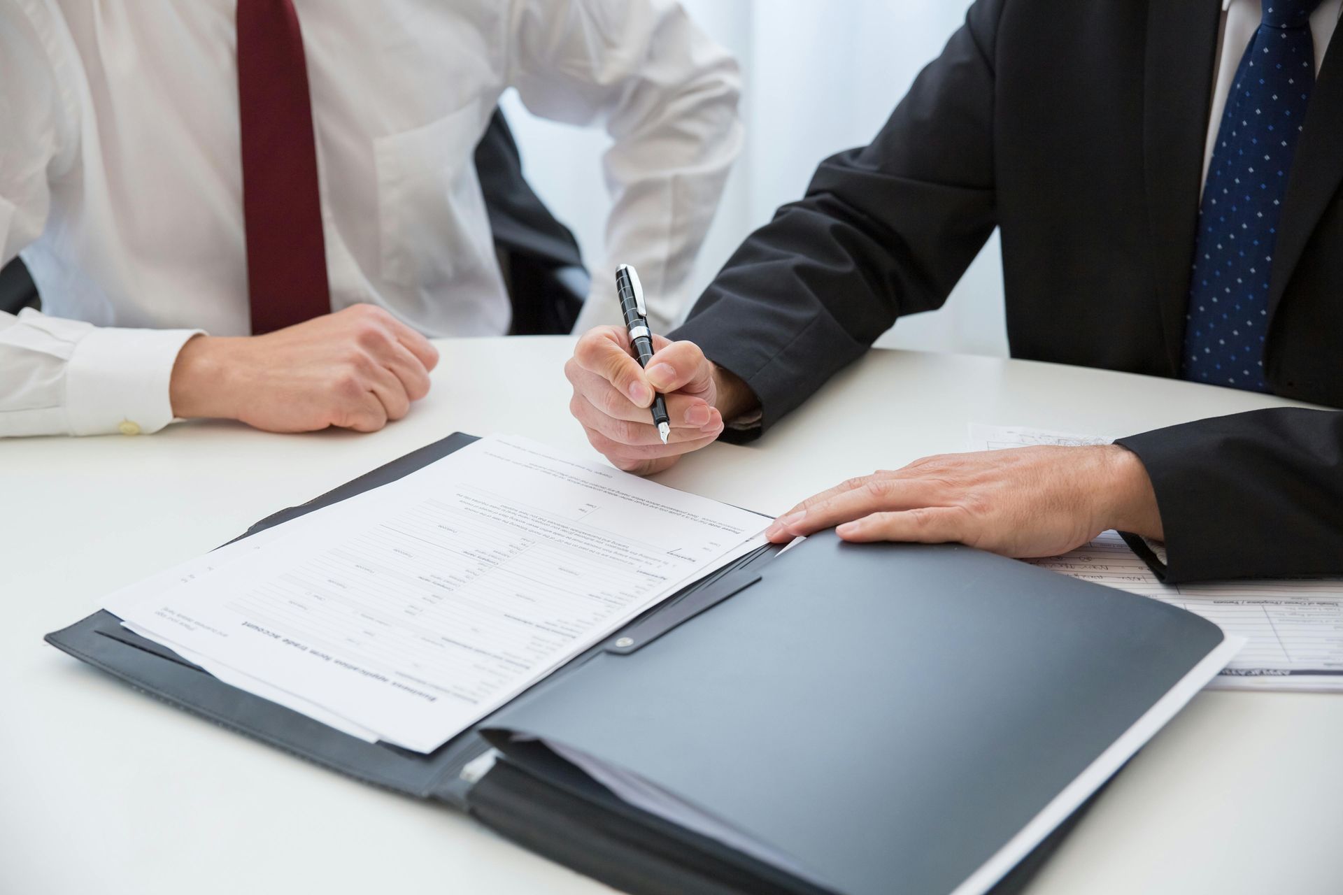 Hands signing an insurance application across a desk.