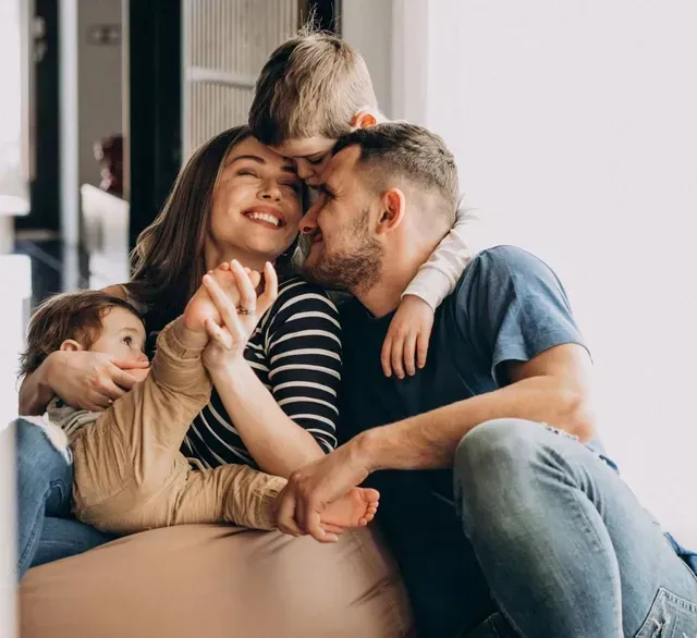 A young couple sitting on the floor at home with their two small children.