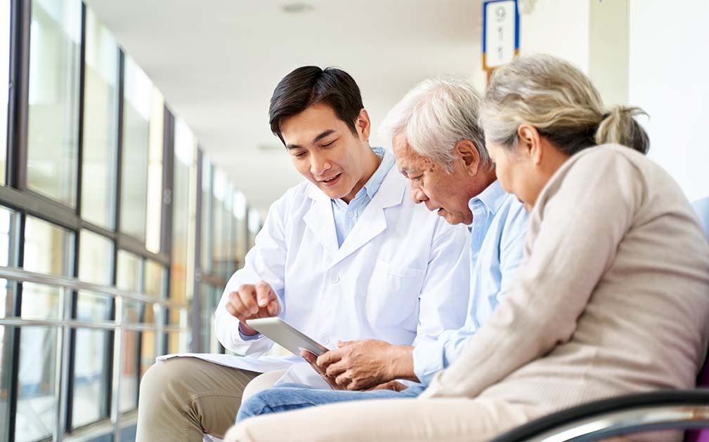 A clinician going through information on a tablet with an older couple.